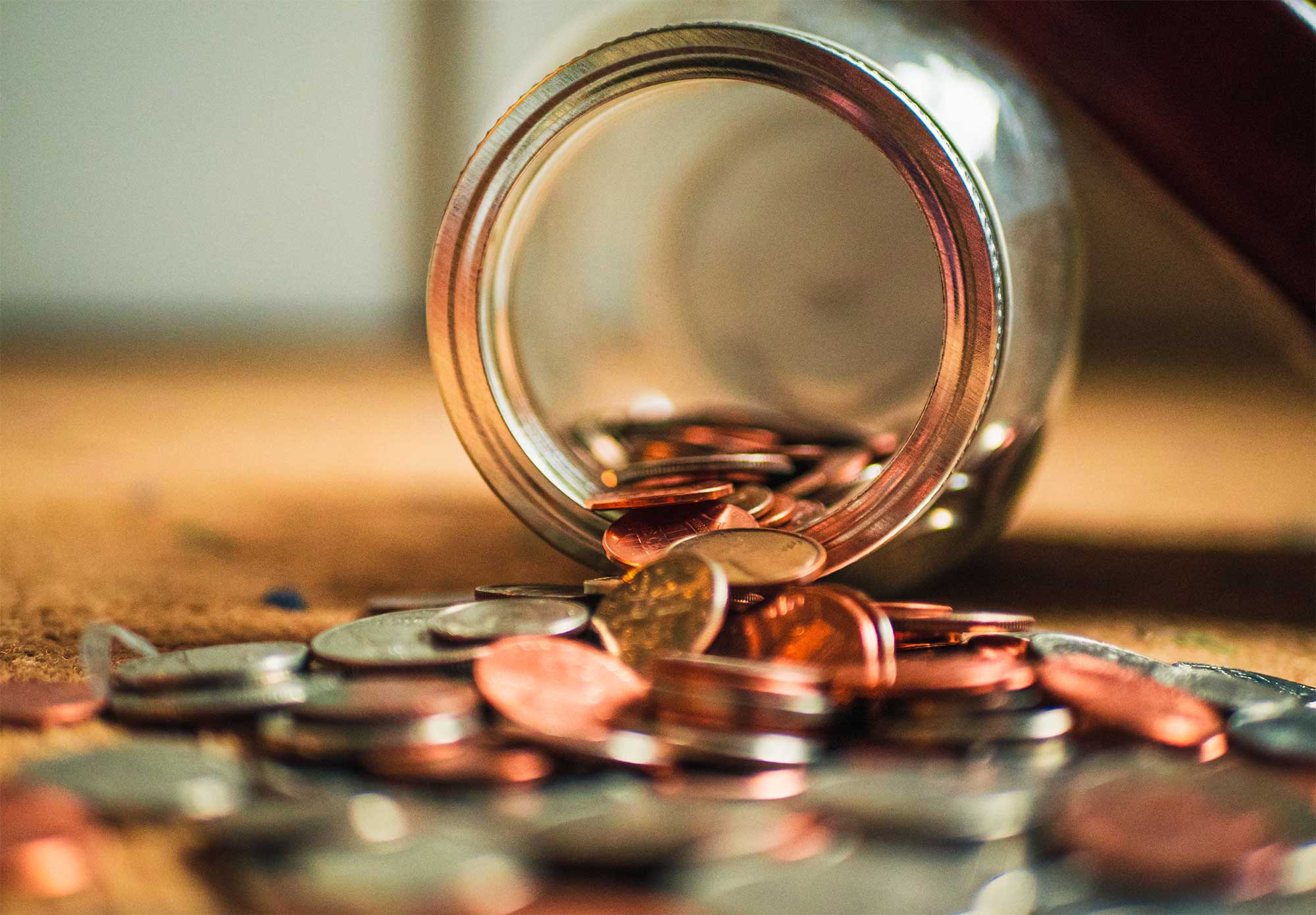  An overturned jar spilling coins represents the search query 'Tips for separating business and personal finances'.